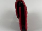 a close up of a red purse on a white surface