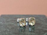 une paire de boucles d'oreilles à clous en saphir jaune posées sur un bloc de marbre