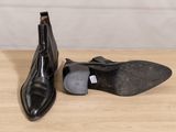 a pair of black leather shoes sitting on top of a wooden table
