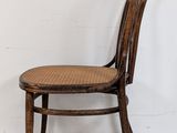an image of a wooden chair with wicker seat against a white wall