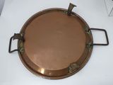 a large copper plate with handles on a white table