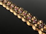 a close up of a gold bracelet with pink and white stones