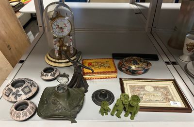 une table sur laquelle se trouvent divers objets, notamment une horloge, une figurine et d'autres objets