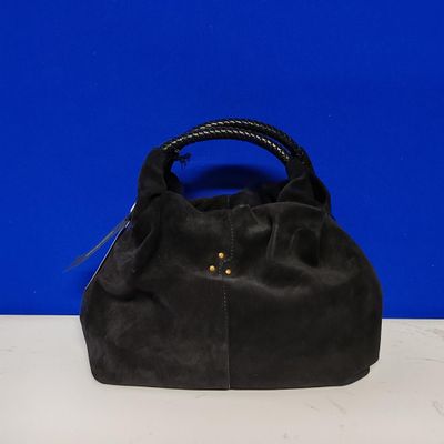un sac à main en cuir noir avec des anses tressées, posé sur une table blanche