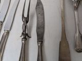 a lot of silverware on a table with knives and spoons