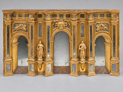 une sculpture en or représentant un homme et une femme devant un miroir