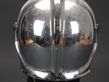 silver helmet on a black stand with a reflection of a building in the background