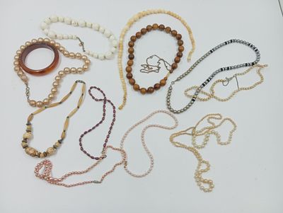 Plusieurs colliers et bracelets sont disposés sur une surface blanche