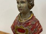 une petite statue représentant un jeune garçon, posée sur une table en bois