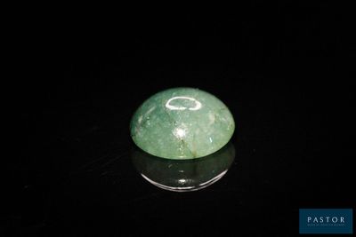 boule de jade verte posée sur une surface noire, avec un fond noir