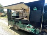 an image of a food truck that is parked in the grass