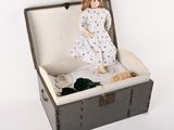 a doll sitting inside of a suitcase on a white surface