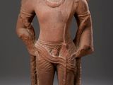une statue antique représentant un homme, les mains dans les poches