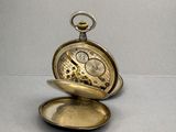 a gold pocket watch sitting on top of a silver plate