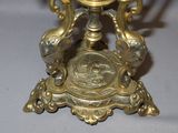 a gold clock on a stand on a white table