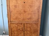 une armoire en bois placée dans un coin de la pièce, sur laquelle est posée une lampe