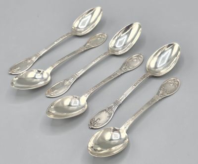 six cuillères en argent et deux cuillères en argent posées sur une surface grise