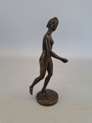statue en bronze représentant une femme marchant, posée sur un socle rond