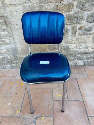 une chaise bleue posée devant un mur de pierre