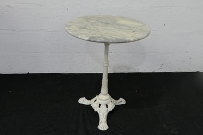 une petite table blanche avec un plateau en marbre posée sur un sol noir
