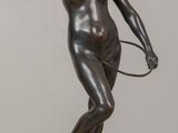 bronze statue of a woman holding a tennis racquet on a table