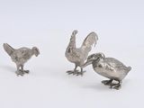trois figurines d'oiseaux en argent sur un fond blanc
