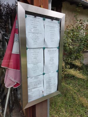 une photo d'un panneau de menu fixé à un poteau en bois