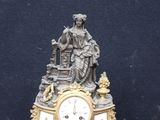a clock with a statue on top of it on a table