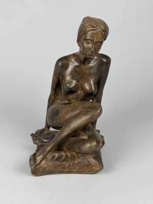 l'image d'une statue de bronze représentant une femme assise sur un rocher