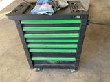un chariot à outils noir et vert sur lequel est posée une serviette