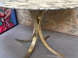 une table en marbre avec un piètement en métal doré dans une pièce