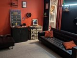 un salon avec un canapé noir et un mur rouge