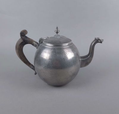 une théière ancienne en argent, avec une anse en forme d'oiseau, sur fond gris