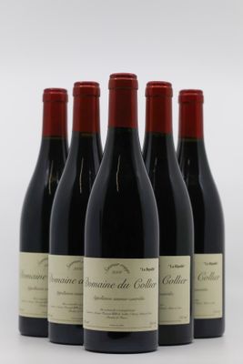 quatre bouteilles de vin rouge sont alignées sur une surface blanche