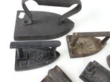 several old irons are sitting on a white surface with a white background