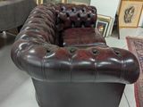 a brown leather couch sitting in a room with pictures on the wall