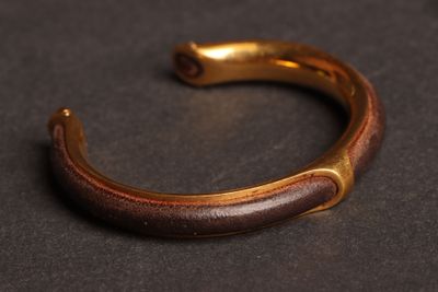 un gros plan d'un bracelet doré et marron posé sur une surface noire