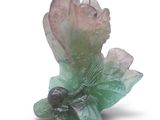 une fleur verte et rose posée sur une surface blanche
