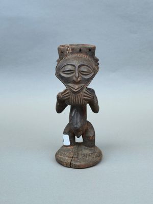 une vieille figurine en bois représentant un homme avec un chapeau sur la tête