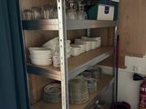 une étagère sur laquelle sont posés de la vaisselle et des tasses, dans la cuisine