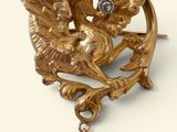 une image représentant une broche en or ornée d'un oiseau et d'une perle