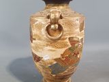 a vase with a handle on it sitting on a table