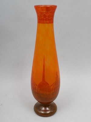 un vase en verre orange posé sur un socle en bois
