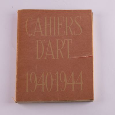 un livre marron aux lettres dorées posé sur une surface blanche
