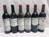 six bottles of red wine are lined up on a table