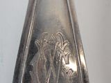 a silver spoon with a design on it sitting on a table