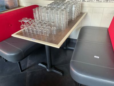 des bouteilles et des verres posés sur une table dans un restaurant avec un banc rouge