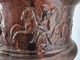 a brown vase with horses on it sitting on a table