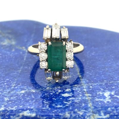 an image of a diamond and emerald ring on a blue stone