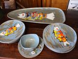 une assiette sur laquelle est peint un poisson, à côté de bols et d'assiettes